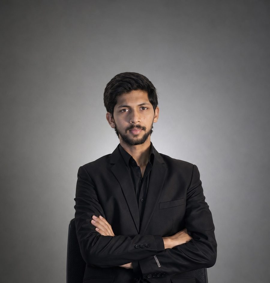 Sami Ahmad in a black suit, seated with arms crossed